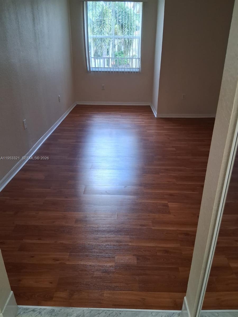 3395 Merrick Court, Unit 1110 Margate, FL 33063 - Photo 7 of 16 an empty room with wooden floor and windows