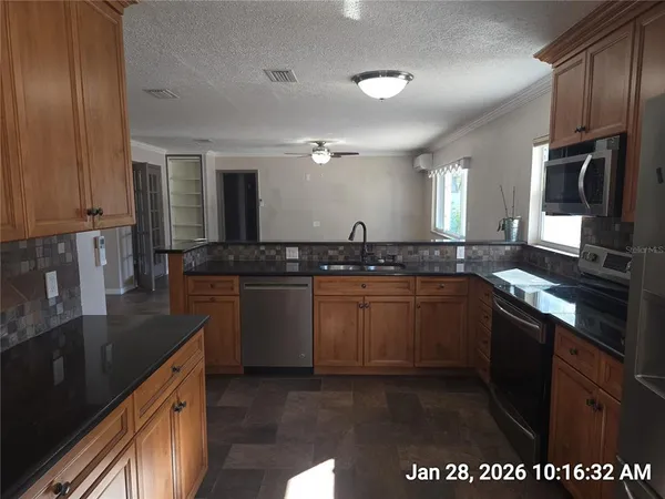 a kitchen with granite countertop a sink cabinets and stainless steel appliances