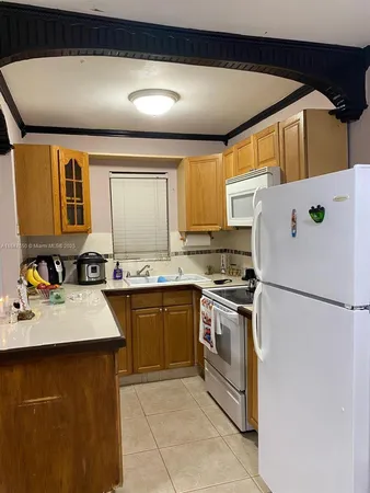 a white kitchen with a sink a stove and a refrigerator