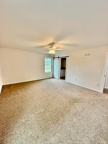 an empty room with chandelier fan and windows