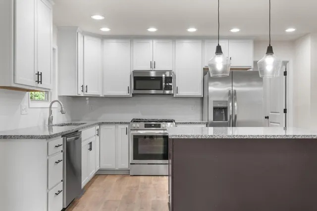 a large kitchen with stainless steel appliances granite countertop a stove a sink and a refrigerator