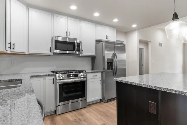 a kitchen with stainless steel appliances granite countertop a stove a refrigerator and a microwave