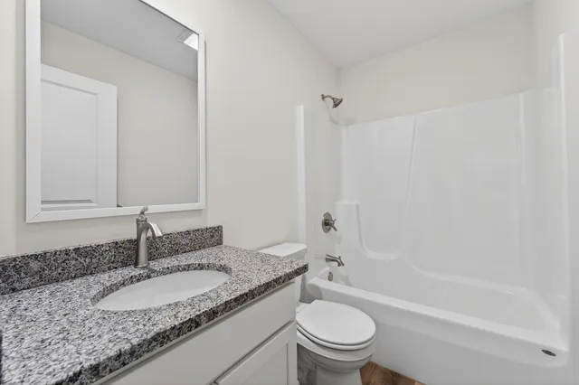 a bathroom with a granite countertop sink toilet and shower