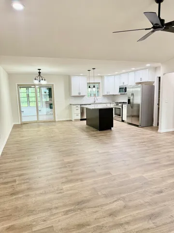 a large room with stainless steel appliances kitchen island granite countertop a stove and a refrigerator