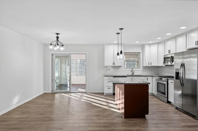 an open kitchen with granite countertop kitchen island wooden floor center island and stainless steel appliances