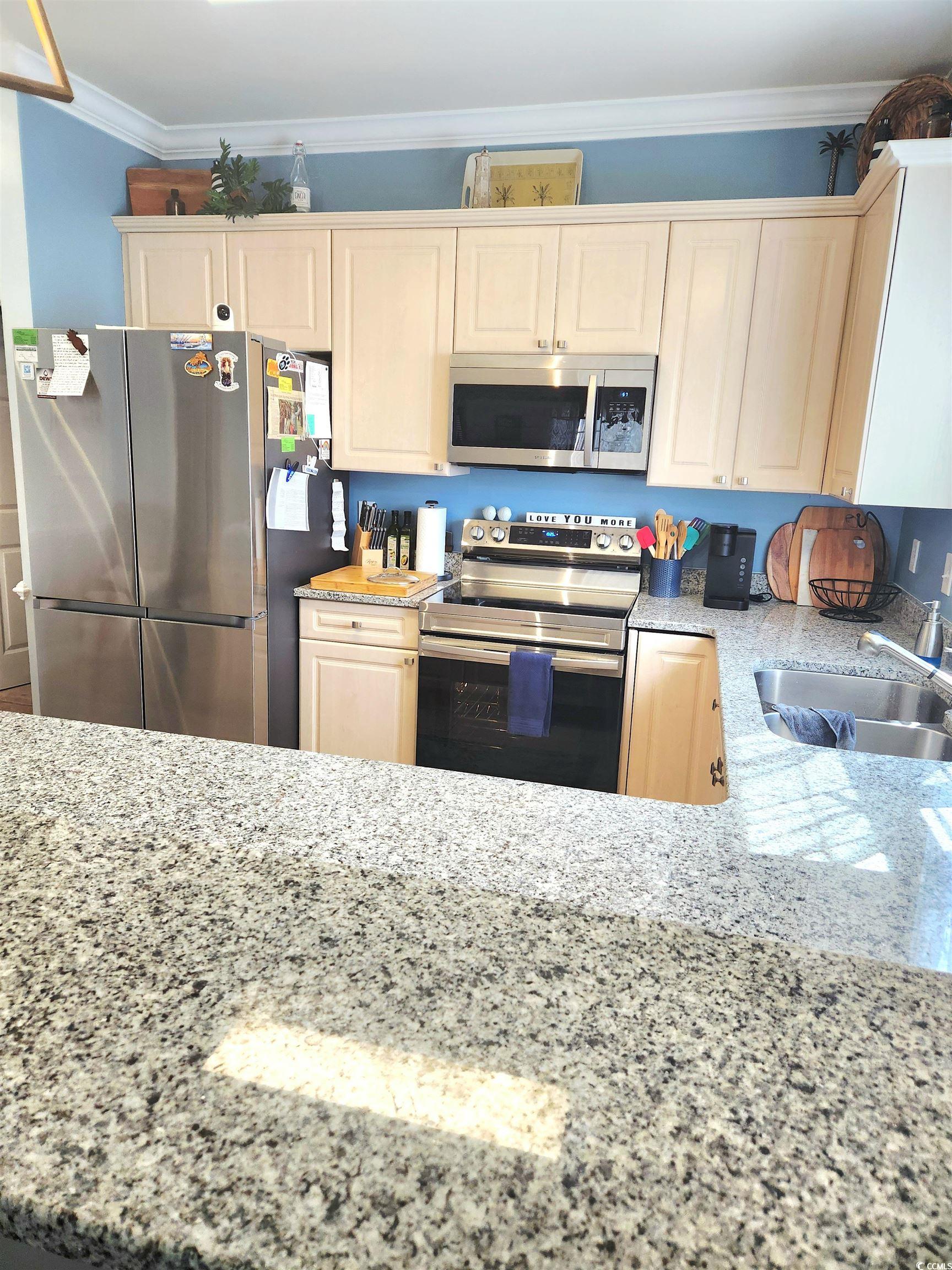 4877 Magnolia Pointe Lane, Unit 201 Myrtle Beach, SC 29577 - Photo 20 of 22 Kitchen with light stone countertops, stainless steel appliances, and crown molding