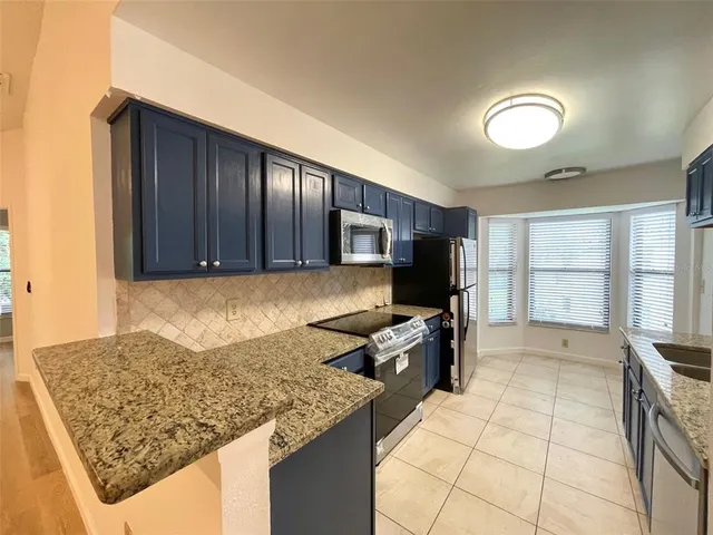 a kitchen with kitchen island granite countertop a stove sink and cabinets