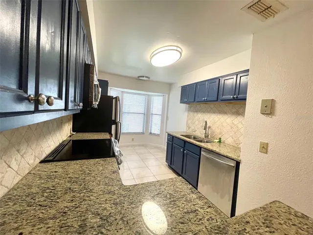 a large kitchen with granite countertop a stove a sink and a granite counter top