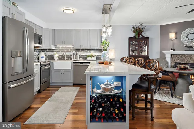 a kitchen with stainless steel appliances granite countertop a refrigerator a stove a sink a dining table and chairs with wooden floor