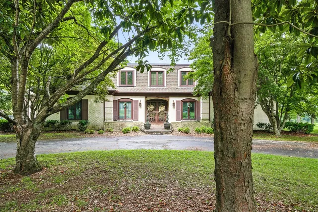 a front view of a house with garden and trees