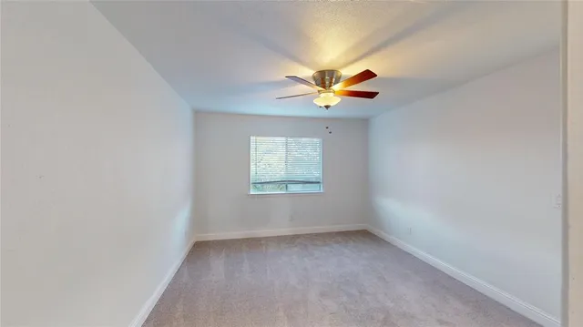 an empty room with a window and a ceiling fan
