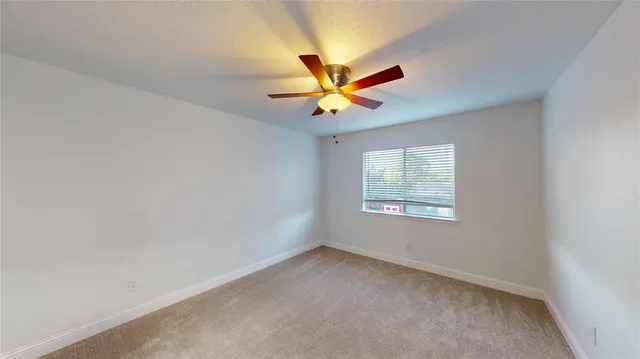 an empty room with a window and a fan