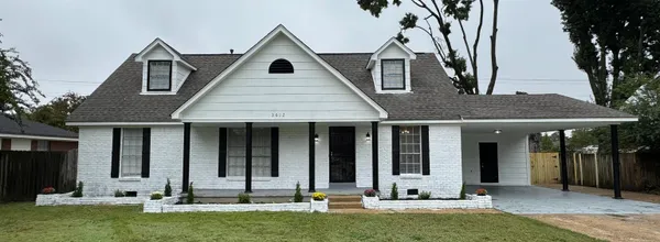 a front view of house with yard and trees in the background