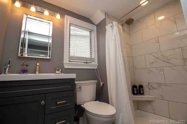 a bathroom with a toilet a sink a mirror a window and vanity