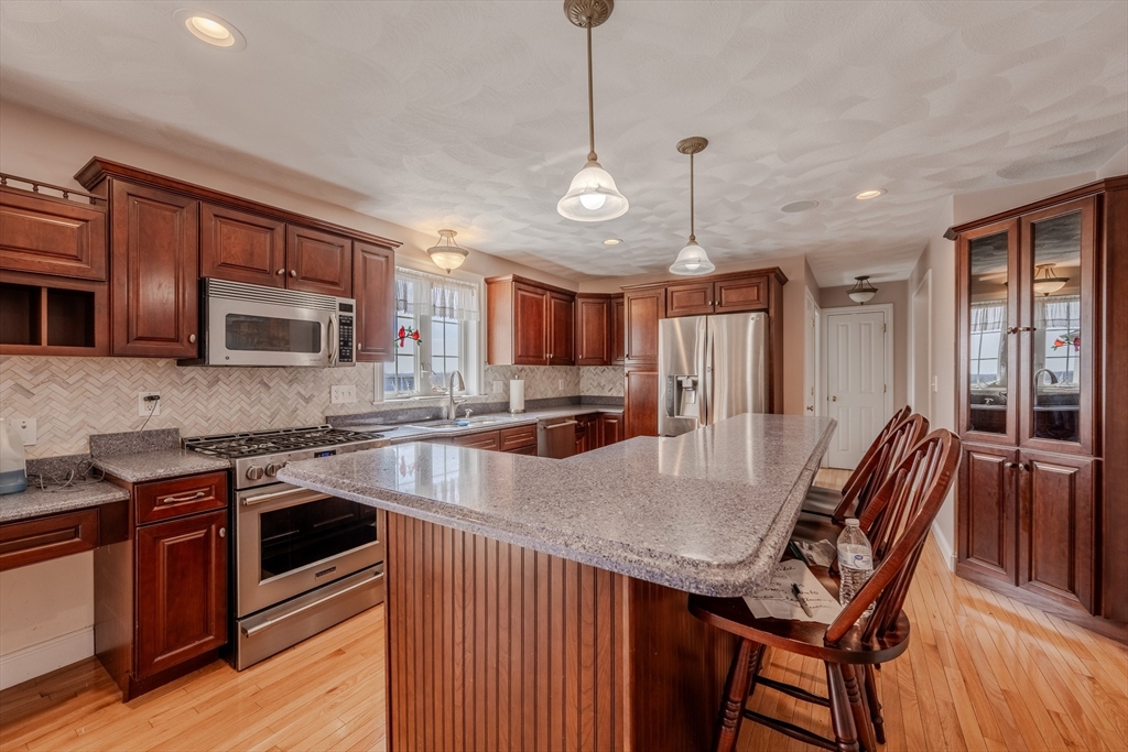 9 Kettle Way Dracut, MA 01826 - Photo 7 of 19 a kitchen with stainless steel appliances granite countertop a stove a sink dishwasher a refrigerator and a dining table with wooden cabinet