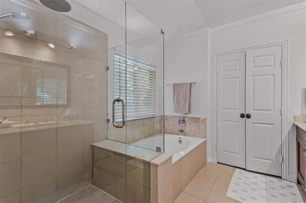 9301 Nottingham Court Rowlett, TX 75088 - Photo 33 of 39 Glass-enclosed shower with rain showerhead, recessed tub with stone surround, and dual paneled doors