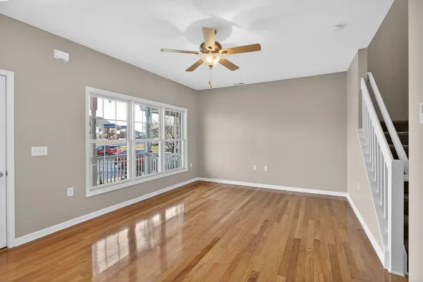 a view of a hallway with wooden floor and a bathroom