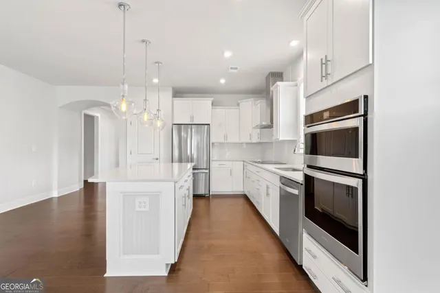 a kitchen with stainless steel appliances kitchen island granite countertop a stove a sink and white cabinets