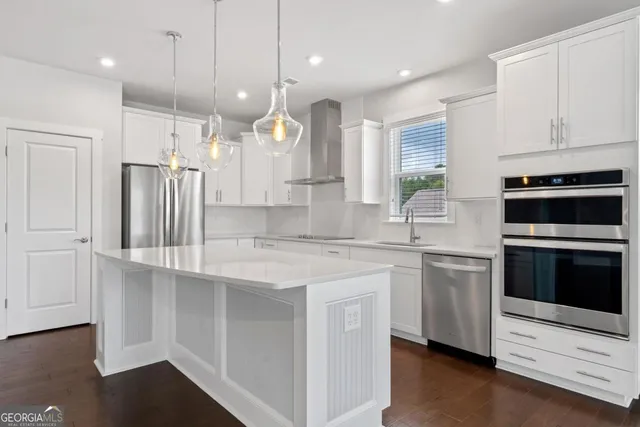 a kitchen with stainless steel appliances granite countertop a sink a stove a refrigerator and island with wooden floor