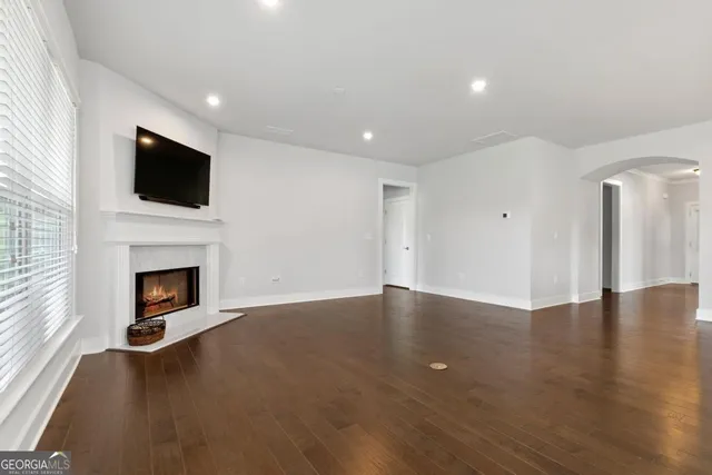 a view of an empty room with wooden floor fireplace and a window