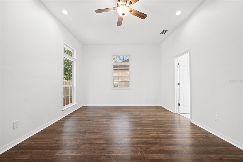 9702 Southwest 35th Lane Gainesville, FL 32608 - Photo 20 of 46 an empty room with wooden floor chandelier fan and windows