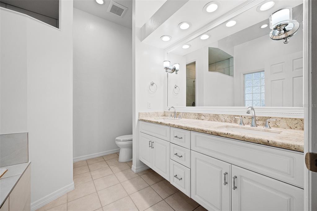 9702 Southwest 35th Lane Gainesville, FL 32608 - Photo 23 of 46 a bathroom with a granite countertop sink a toilet and a mirror