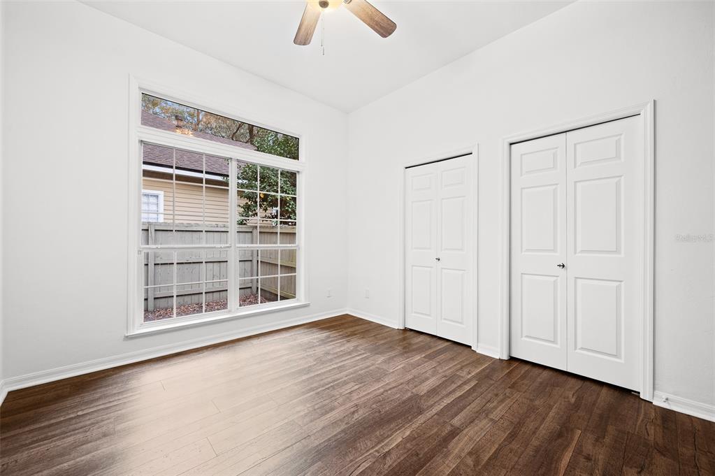 9702 Southwest 35th Lane Gainesville, FL 32608 - Photo 27 of 46 an empty room with wooden floor chandelier fan and windows