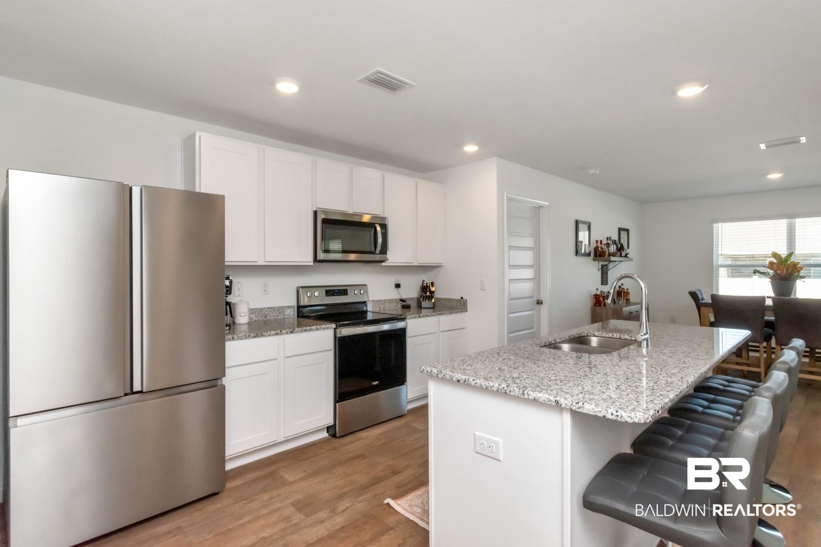 10921 Northern Dancer Court Daphne, AL 36526 - Photo 15 of 32 Kitchen with white cabinets, an island with sink, appliances with stainless steel finishes, light wood-type flooring, and sink