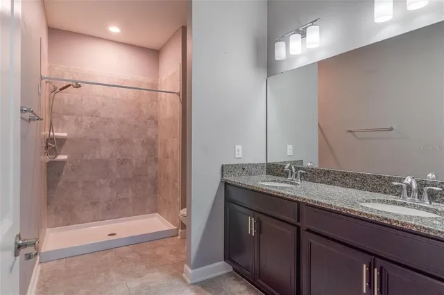 a bathroom with a granite countertop sink a toilet and shower