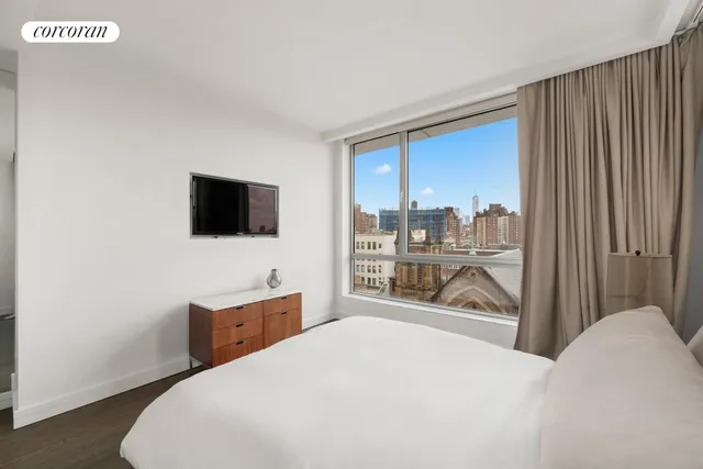 a bedroom with a bed and a flat tv screen next to a window