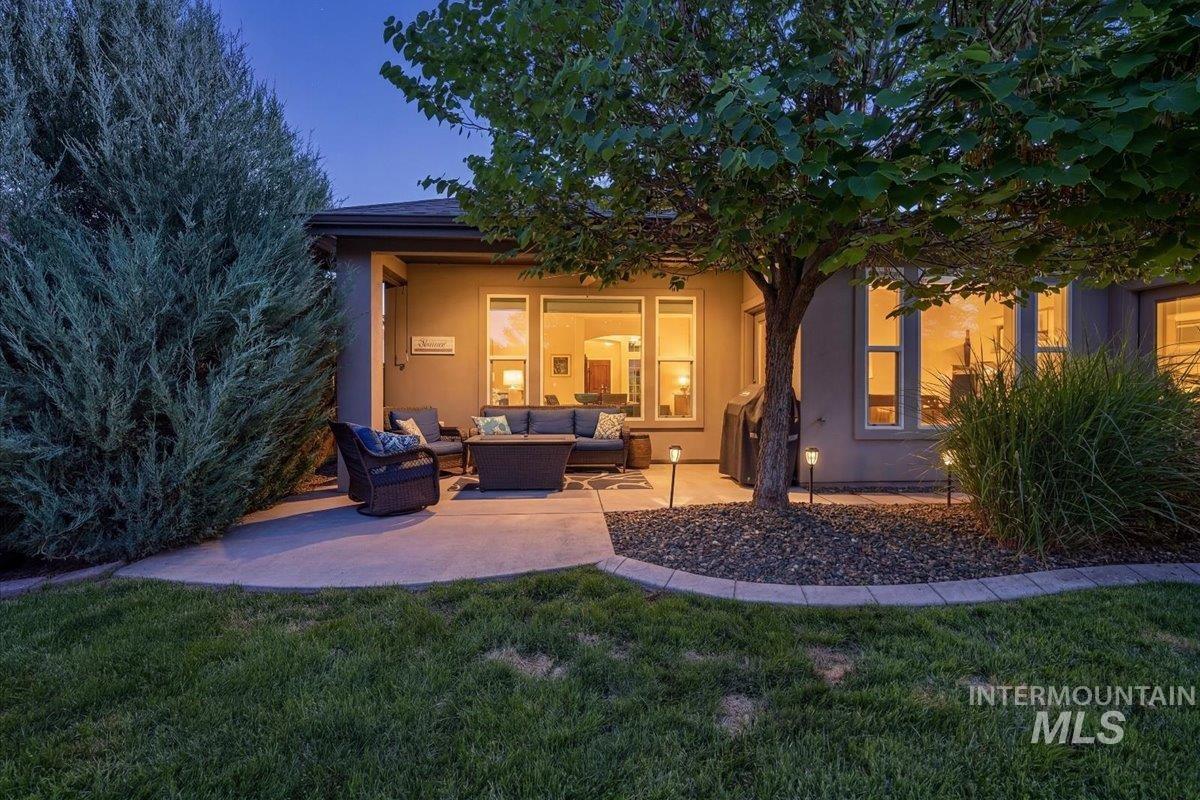 1303 West Brando Street Meridian, ID 83646 - Photo 35 of 49 Expansive concrete patio with a stucco exterior, multiple large windows, landscaped rock beds, and a mature tree