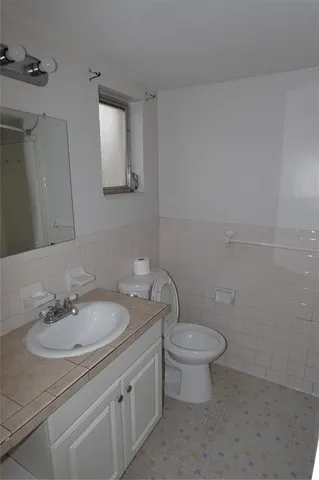 a bathroom with a granite countertop sink a toilet and mirror