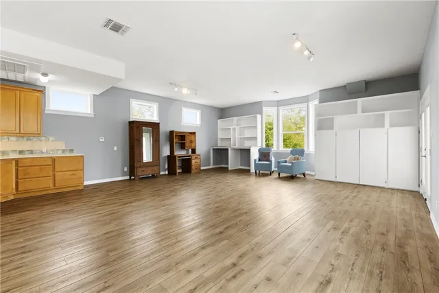 a view of an empty room with a window and a kitchen
