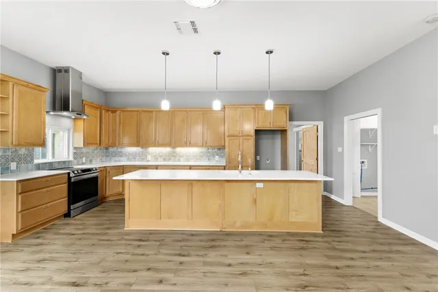 a large kitchen with a large counter top a sink stainless steel appliances and cabinets