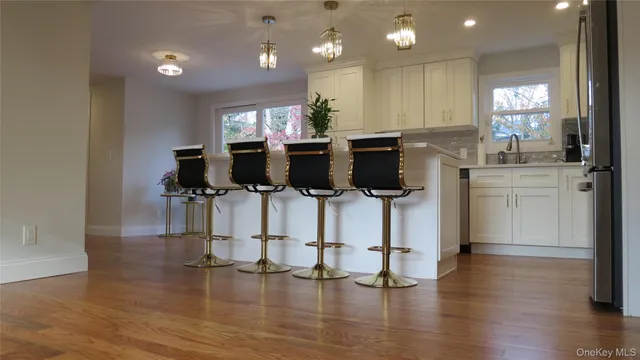 a kitchen with stainless steel appliances kitchen island granite countertop a stove top oven a sink dishwasher and a refrigerator with wooden floor