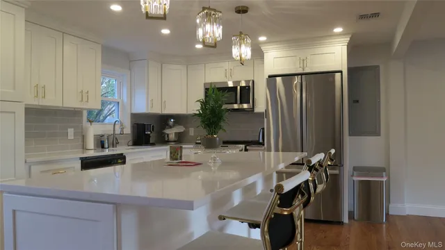 a kitchen with kitchen island a counter top space a sink a refrigerator and cabinets