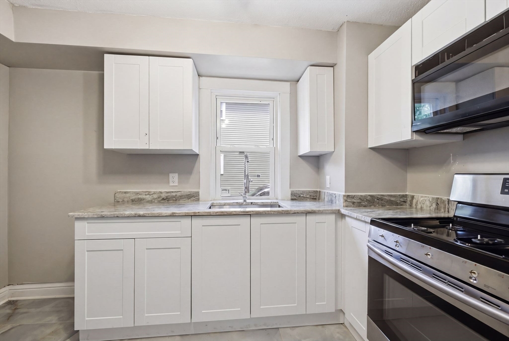 62 Kenyon Street Springfield, MA 01109 - Photo 13 of 26 a kitchen with granite countertop white cabinets and stainless steel appliances