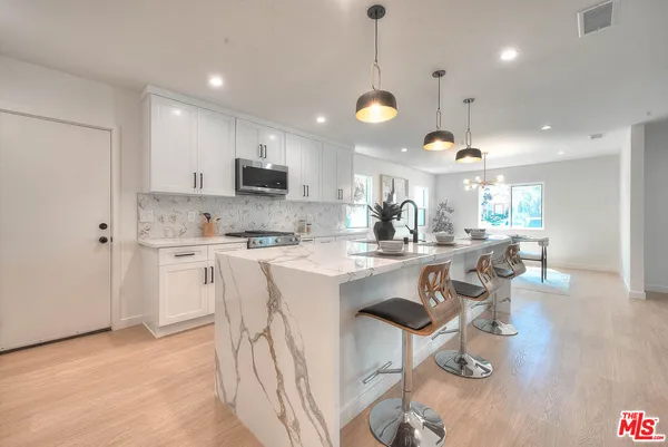 a large white kitchen with cabinets a sink and appliances