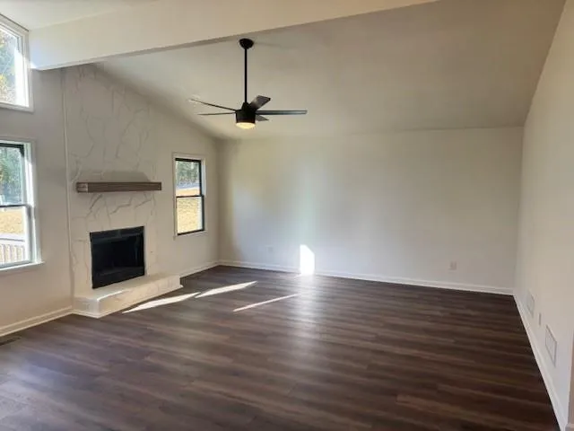 a view of an empty room with wooden floor fireplace and a window