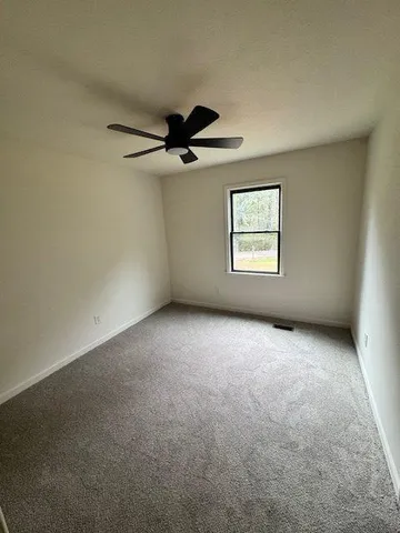 an empty room with windows and ceiling fan