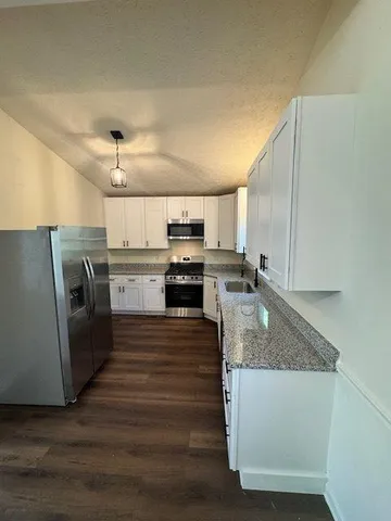 a large kitchen with stainless steel appliances granite countertop a stove a sink and a refrigerator