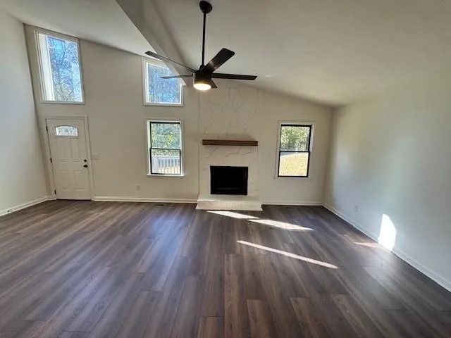 an empty room with wooden floor a ceiling fan and windows