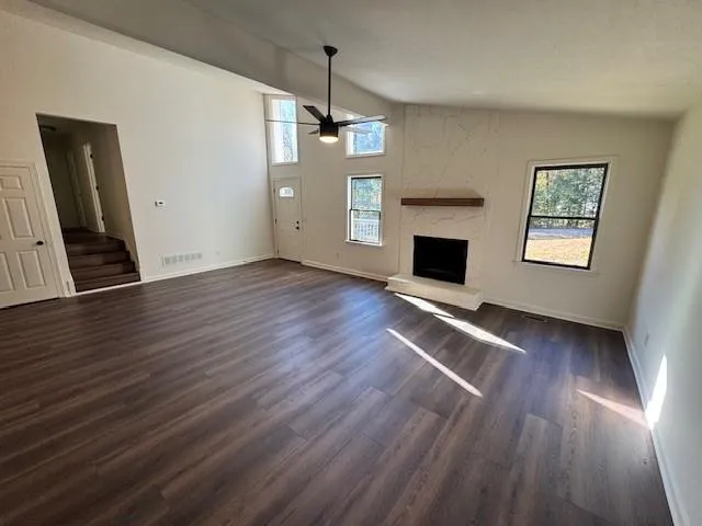 an empty room with wooden floor fireplace and windows