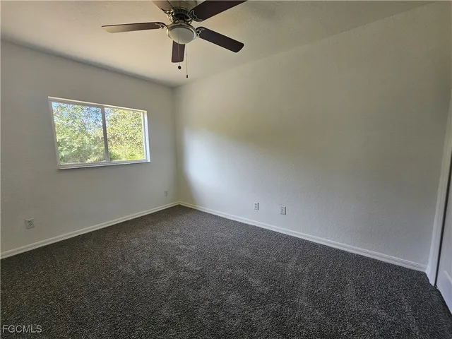 an empty room with windows and ceiling fan