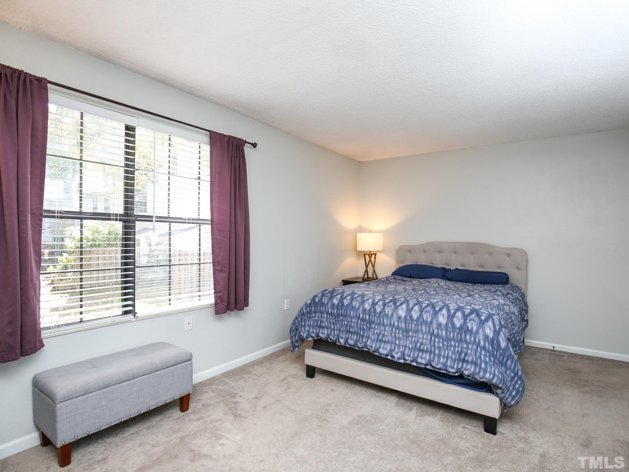 2429 Condor Court, Unit 2429 Raleigh, NC 27615 - Photo 16 of 26 a bedroom with a bed and a couch with exposed radiator