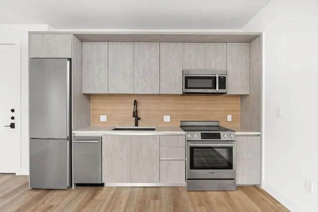 a kitchen with cabinets stainless steel appliances and wooden floor