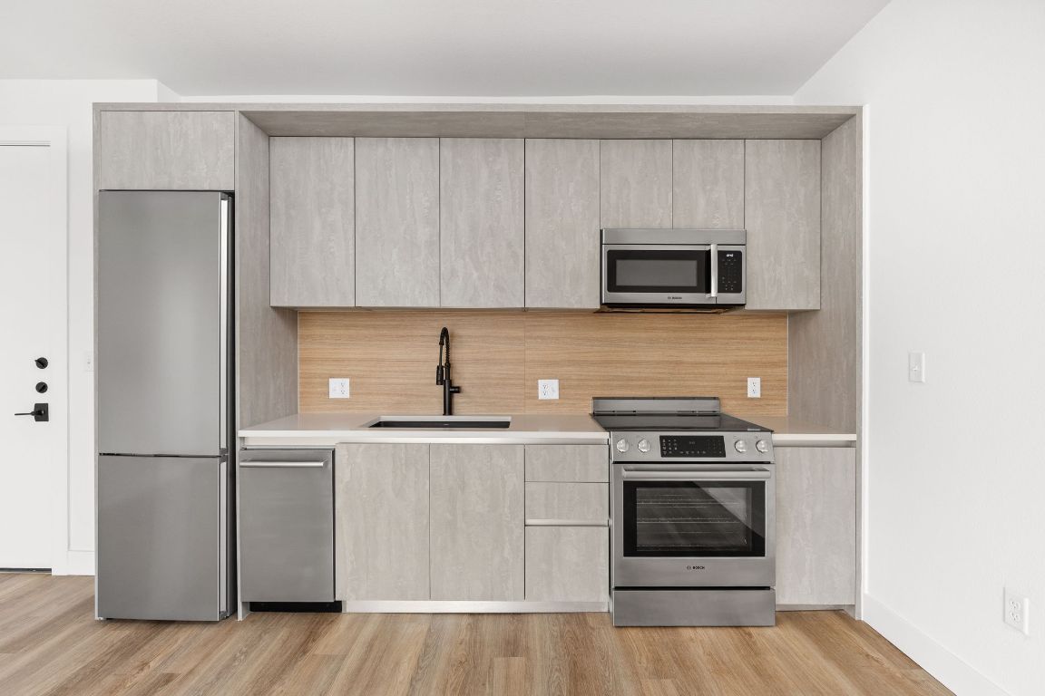 a kitchen with cabinets stainless steel appliances and wooden floor