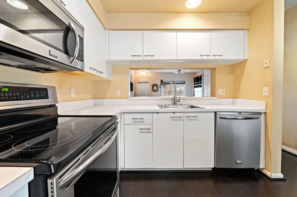 a kitchen with granite countertop a sink cabinets and stainless steel appliances