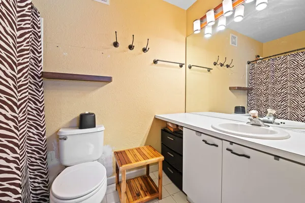 a bathroom with a sink a toilet a mirror and shower curtain