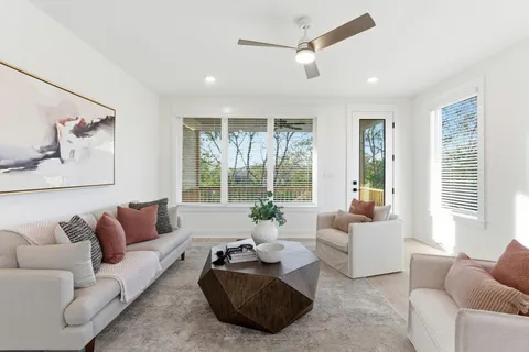 a living room with furniture ceiling fan and a large window